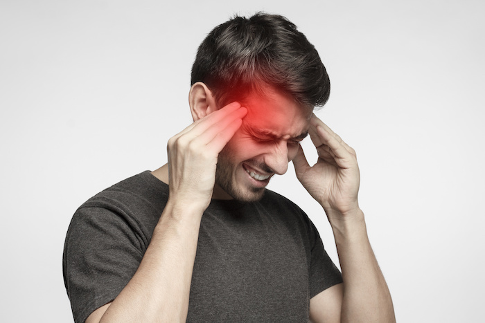Closeup of a young man with a migraine headache.