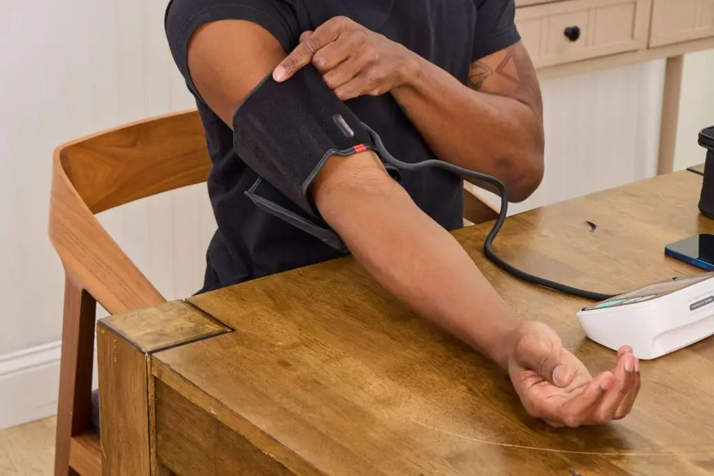 Adult in their 30s checking blood pressure with home monitor