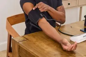 Adult in their 30s checking blood pressure with home monitor